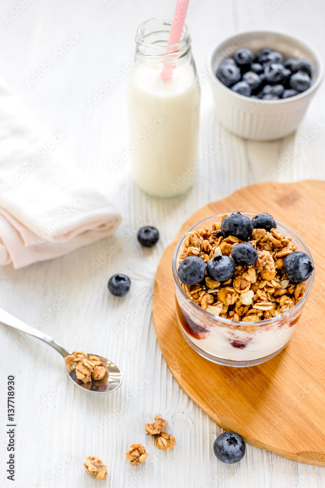 Fitness breakfast with granola, milk and berries on white background