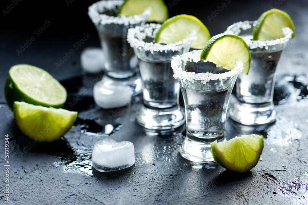 Tequila shot with salt and ice on dark background