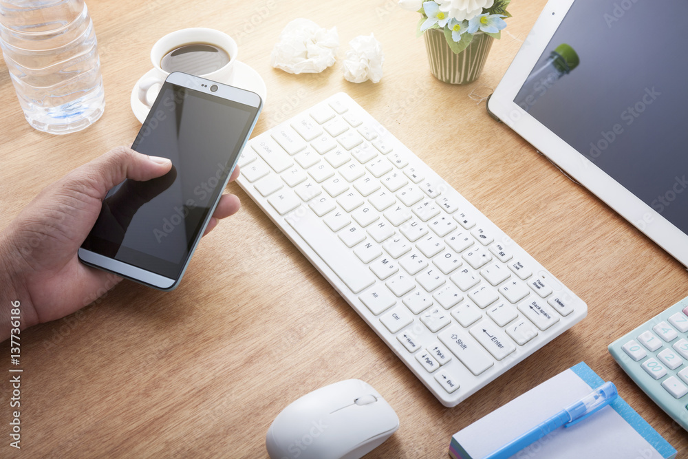 Hand man use tablet smartphone with Office desk wood table of Business workplace and business object