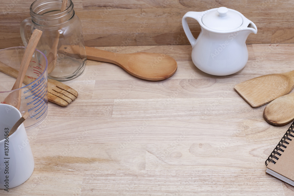 measuring cup and wooden spoon, cooking supplies on wood background