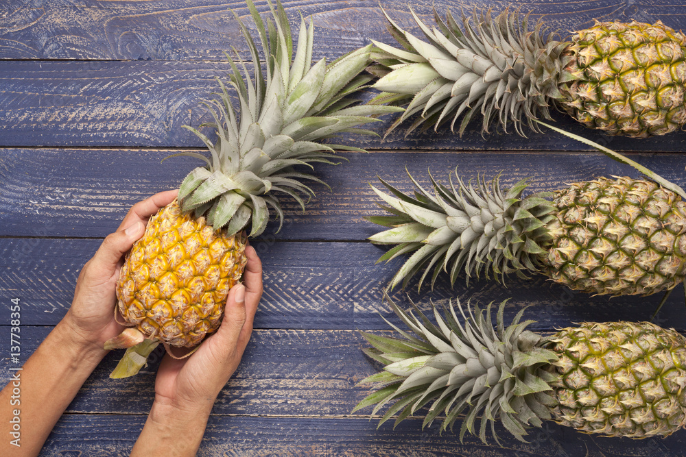 Row of pineapple fruits on wooden table background.