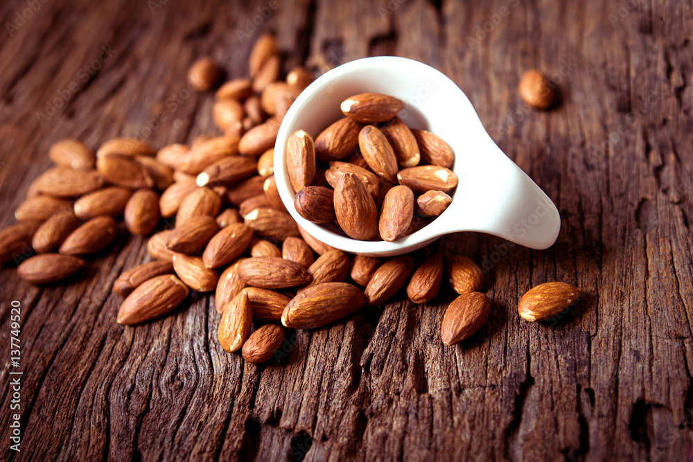 close up Peeled almonds nut  in small white cup on wooden  background