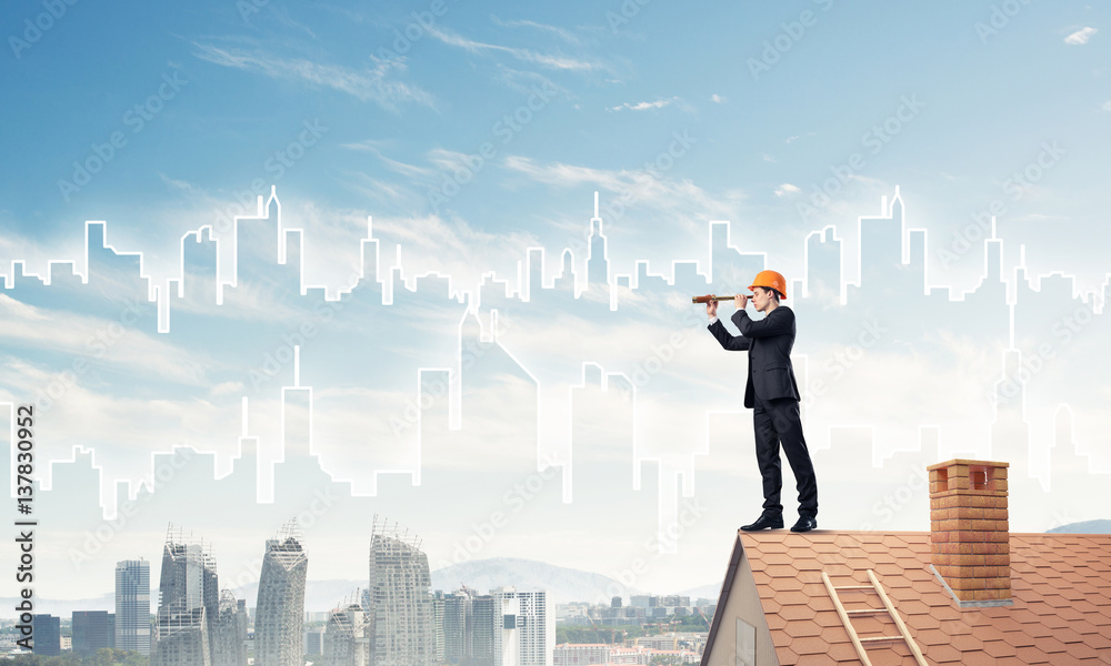 Engineer man standing on roof and looking in spyglass. Mixed med