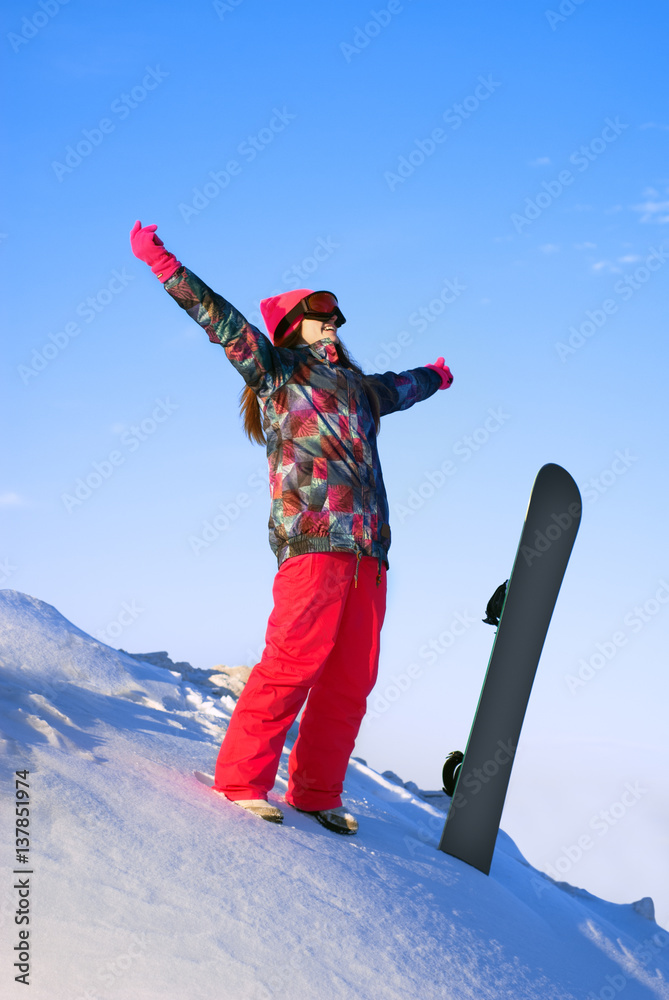 happy girl standing on a mountain top with snowboard