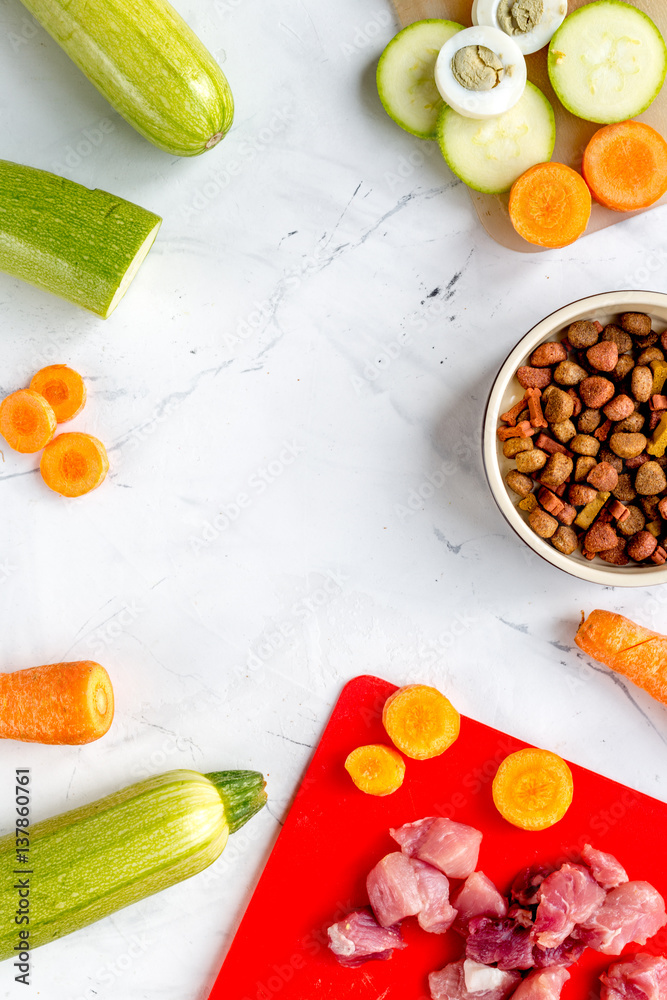 Bowl of dry dogfood, carrot, courgette, meat table background top view mock-up