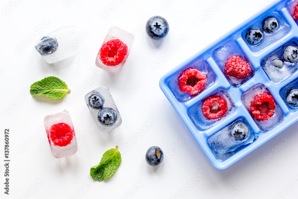 blueberry and raspberry in icetray on stone background top view