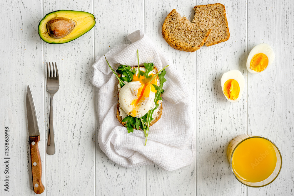 sandwich with poached eggs on wooden background top view