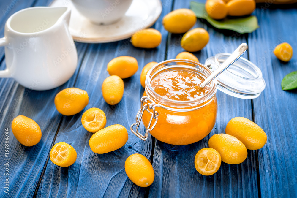 kumquat on plate and jam in jar at wooden table