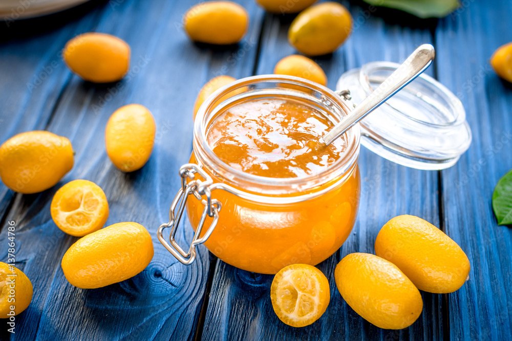 kumquat on plate and jam in jar at wooden table