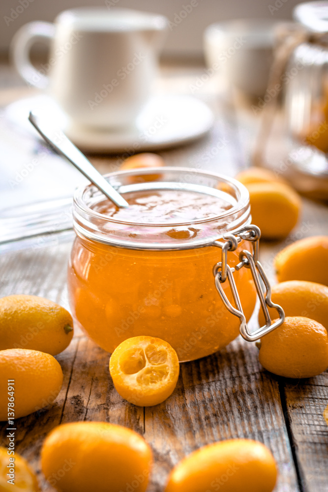 kumquat on plate and jam in jar at wooden table