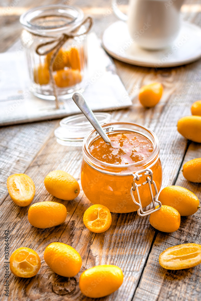 kumquat on plate and jam in jar at wooden table