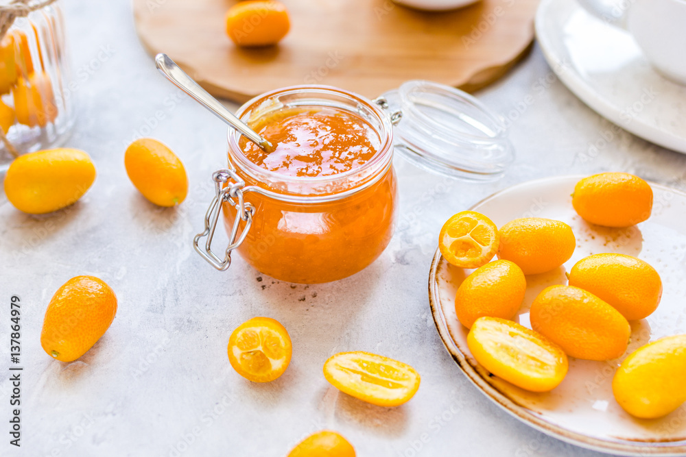 kumquat on plate and jam in jar at gray background