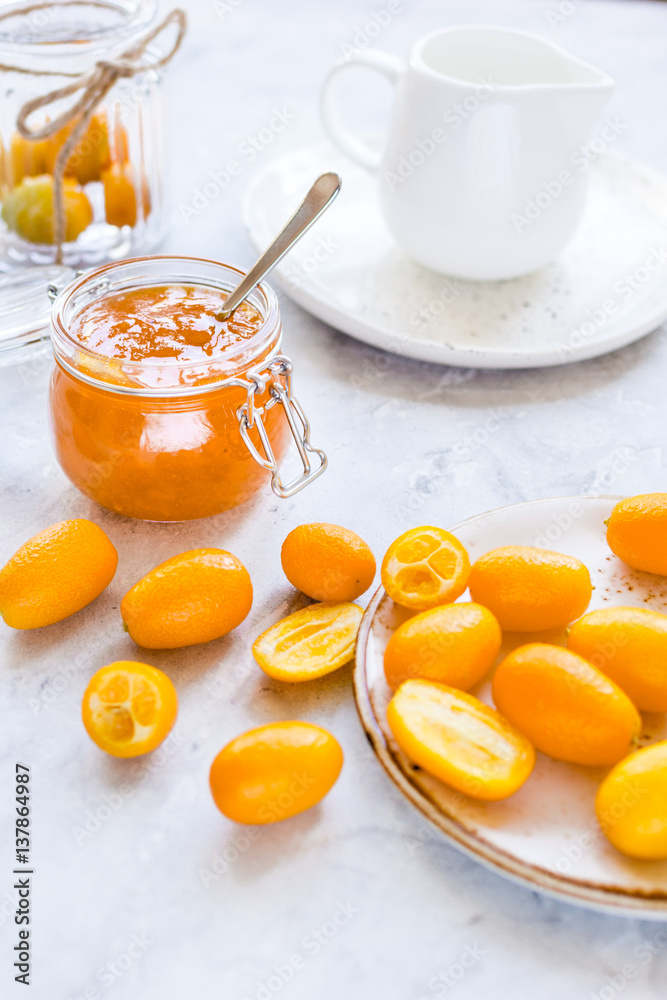 kumquat on plate and jam in jar at gray background