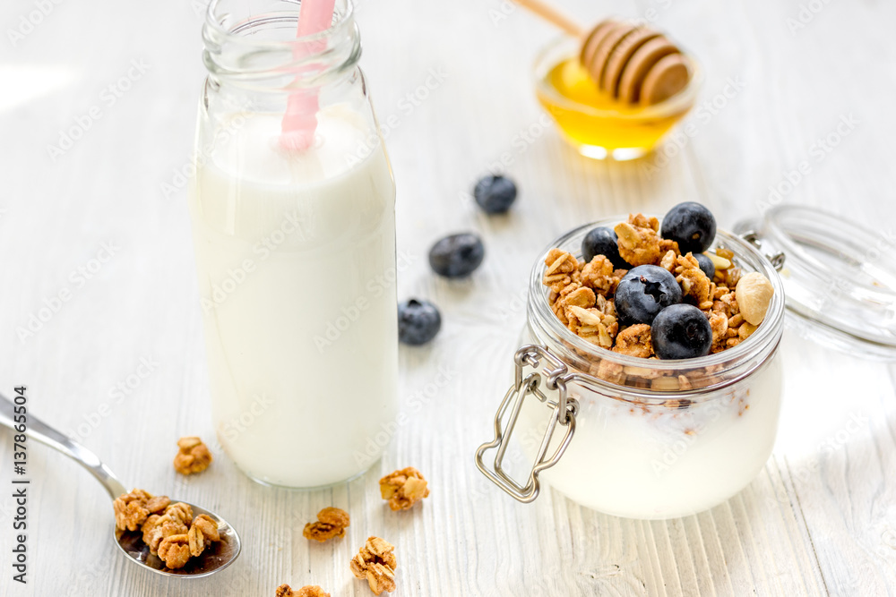 Homemade granola with blueberries in jar on white kitchen background