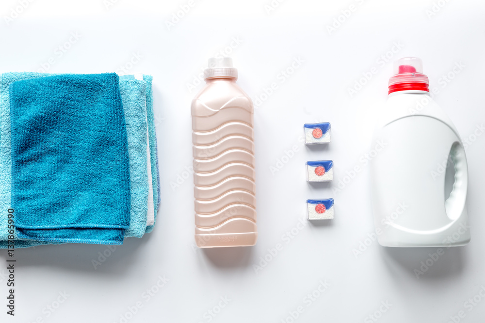 Pile of towels with detergent on white background top view