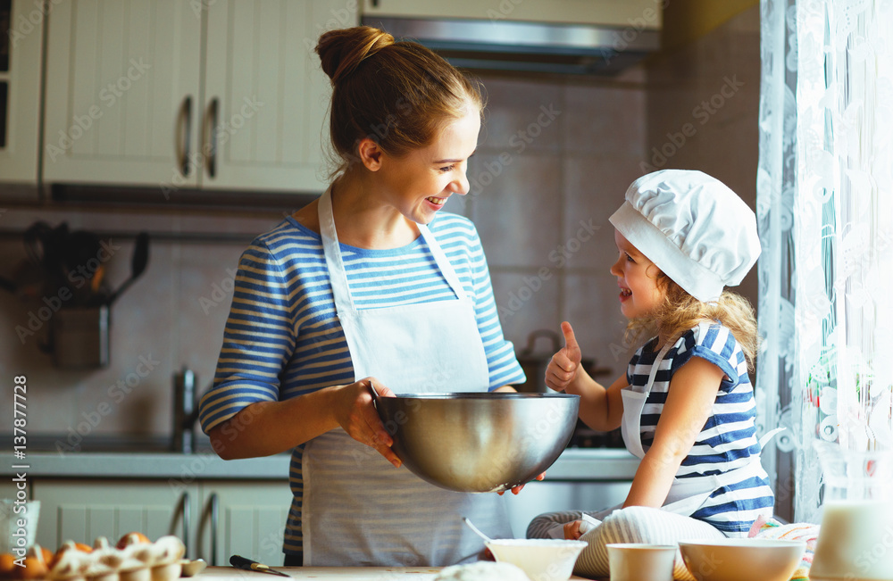 happy family in kitchen. mother and child preparing dough, bake cookies