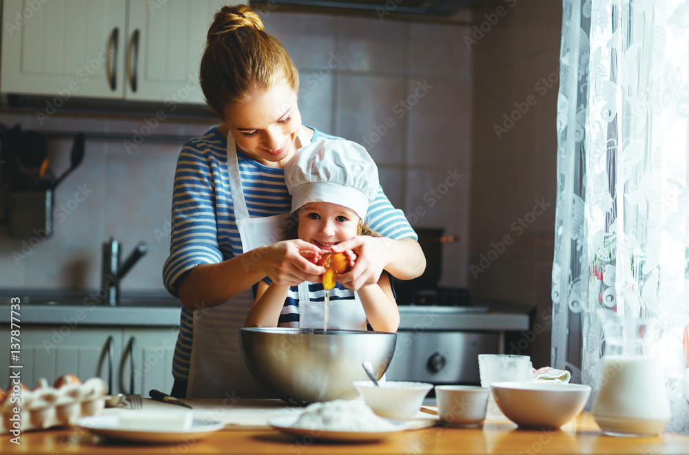 happy family in kitchen. mother and child preparing dough, bake cookies