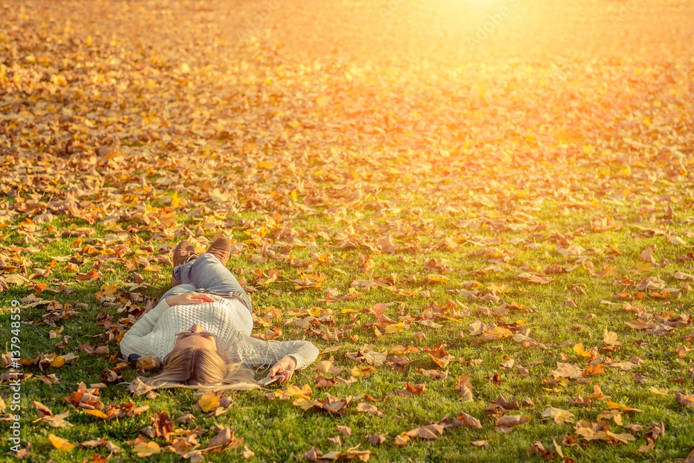 Woman listening music on grass at autumn time