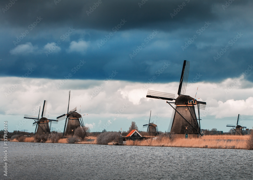 Windmills against cloudy sky at sunset in famous Kinderdijk, Netherlands. Rustic landscape with dutc