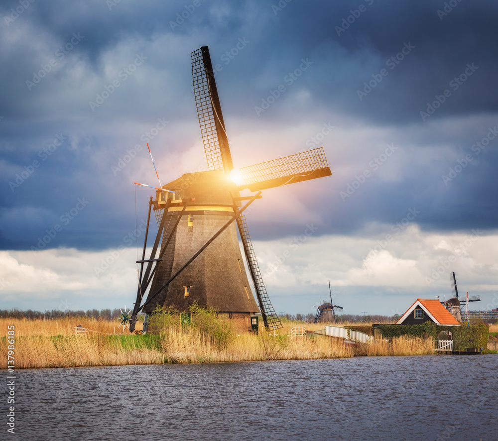 Windmills against cloudy sky at sunset in famous Kinderdijk, Netherlands. Rustic landscape with dutc