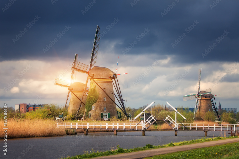 Windmills against cloudy sky at sunset in famous Kinderdijk, Netherlands. Rustic landscape with trad