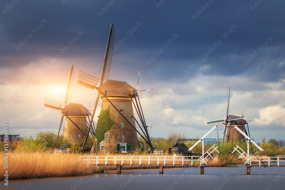 Windmills against cloudy sky at sunset in famous Kinderdijk, Netherlands. Rustic landscape with trad