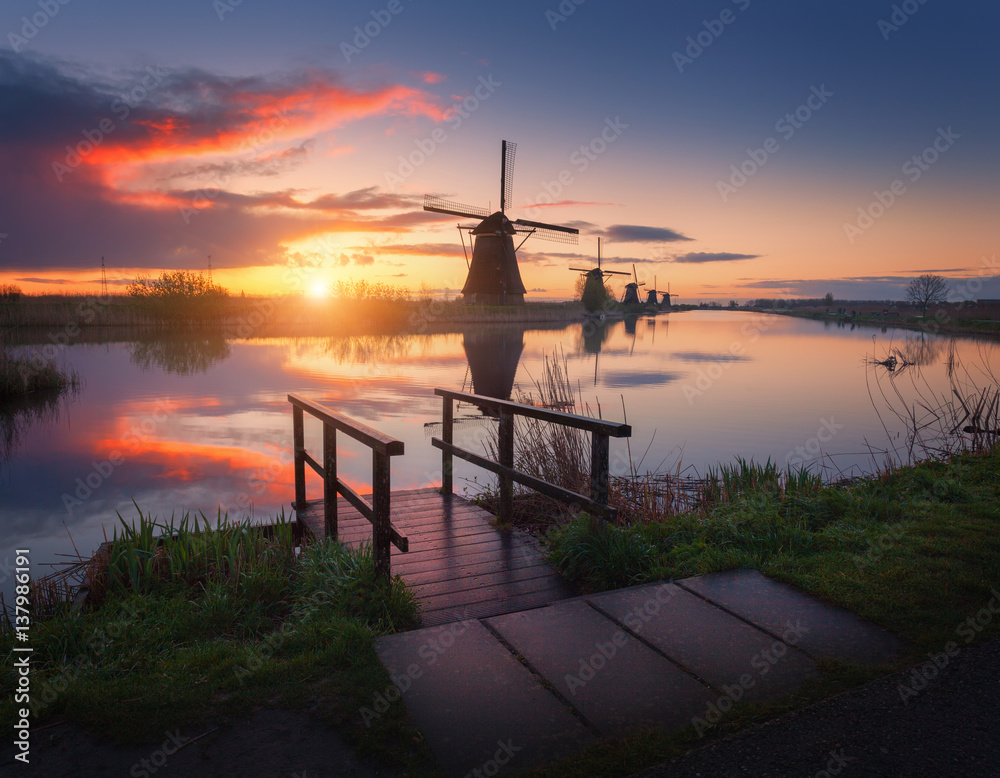 Silhouette of windmills at sunrise in Kinderdijk, Netherlands. Rustic landscape with wooden pier aga