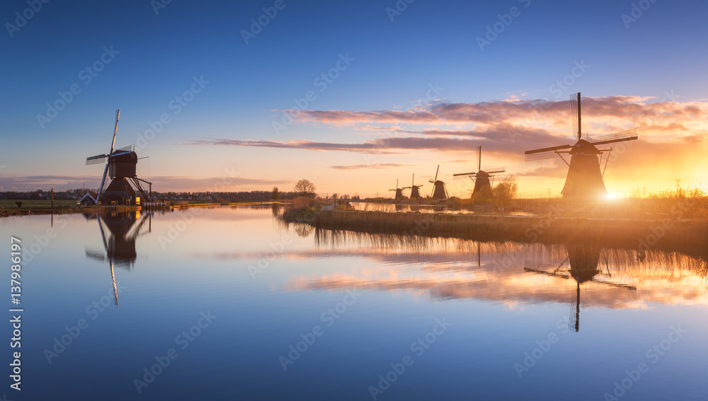 Silhouette of windmills at amazing foggy sunrise in Kinderdijk, Netherlands. Rustic landscape with d