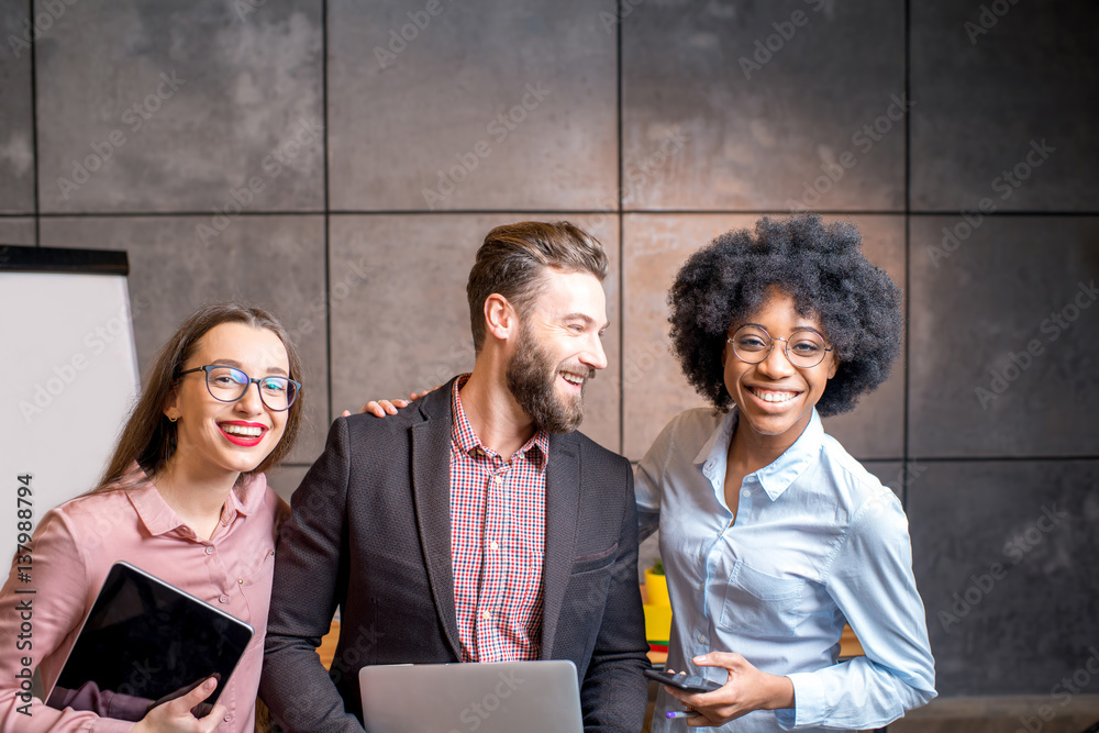 Portrait of three happy multi ethnic coworkers together at the office