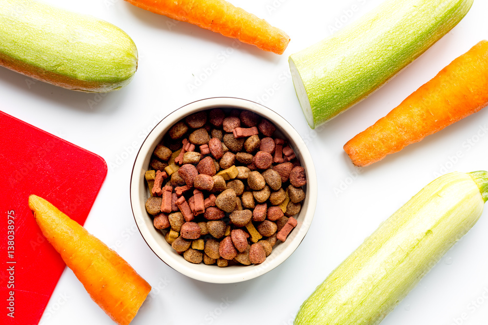 Dry dogfood with carrot and zucchini on table background top view