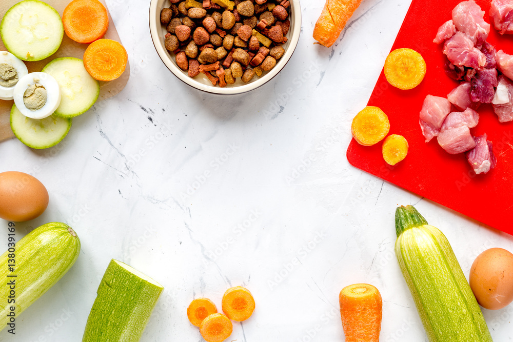 Bowl of dry dogfood, carrot, courgette, meat table background top view mock-up