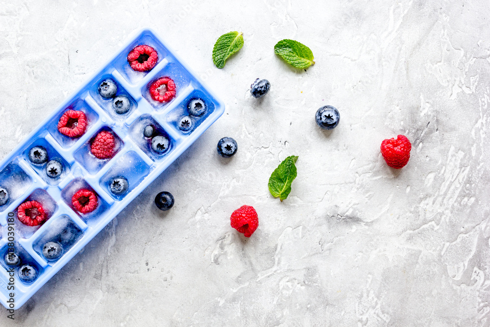 blueberry and raspberry in icetray on stone background top view mock-up