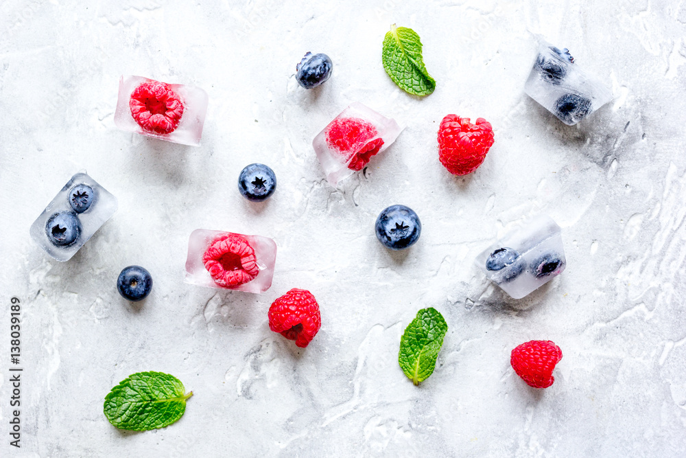 fresh berries with mint in ice cubes on stone background top view