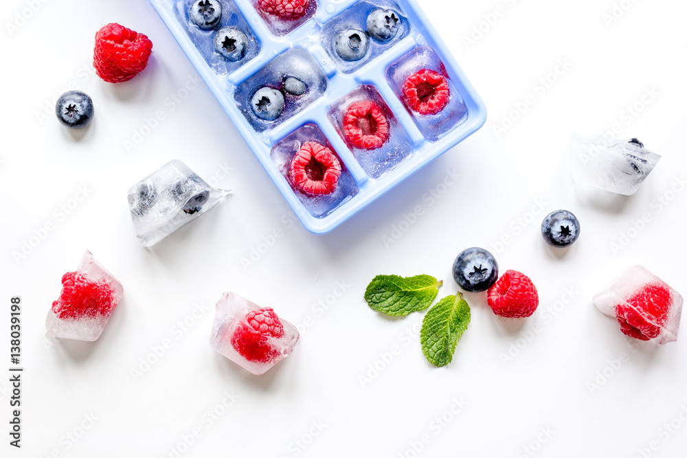 Ice tray with berries and mint on white background top view