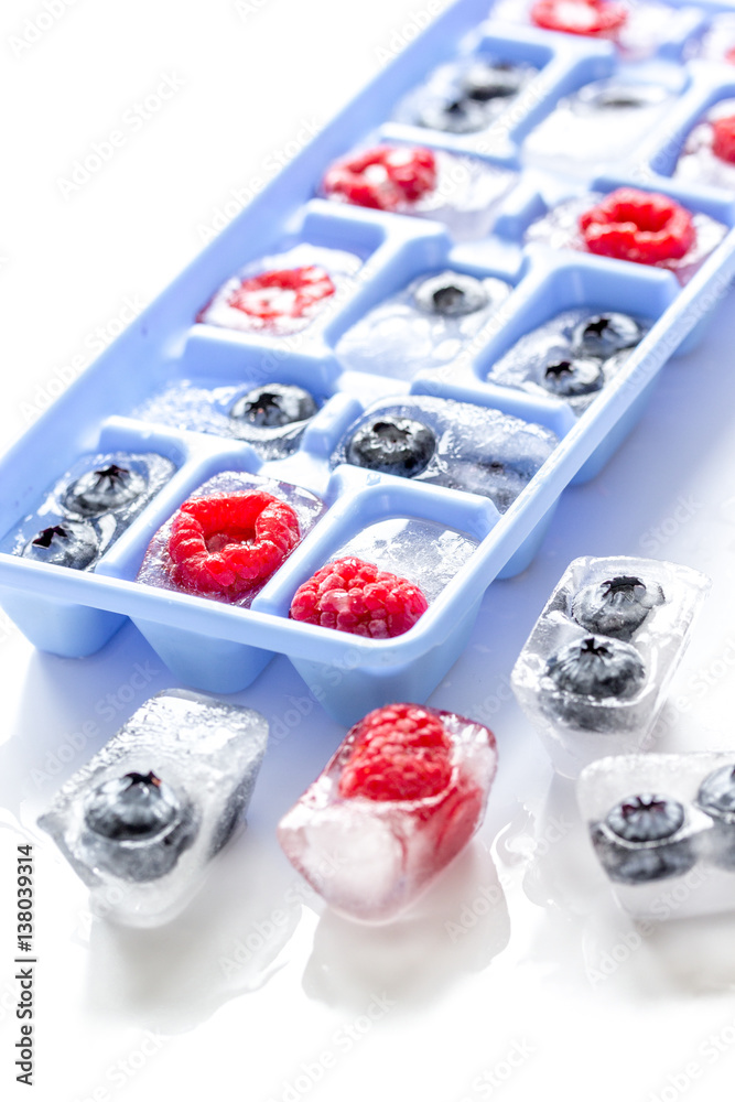 blueberry and raspberry in icetray on stone background