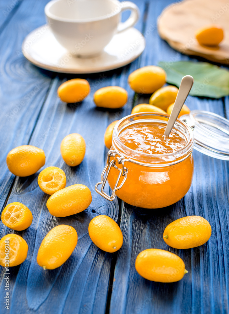 kumquat on plate and jam in jar at wooden table