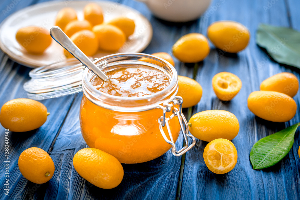 kumquat on plate and jam in jar at wooden table