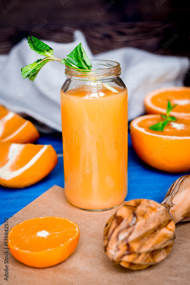 healthy orange cocktail with mint leaves in bottle on kitchen background