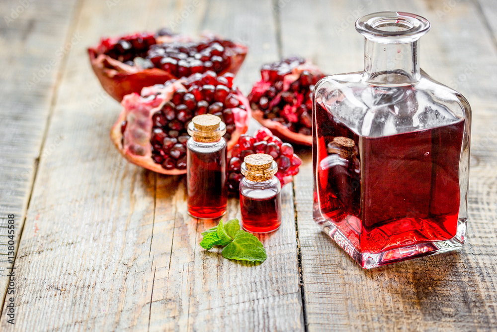 sliced pomegranate and extract in glass on wooden background