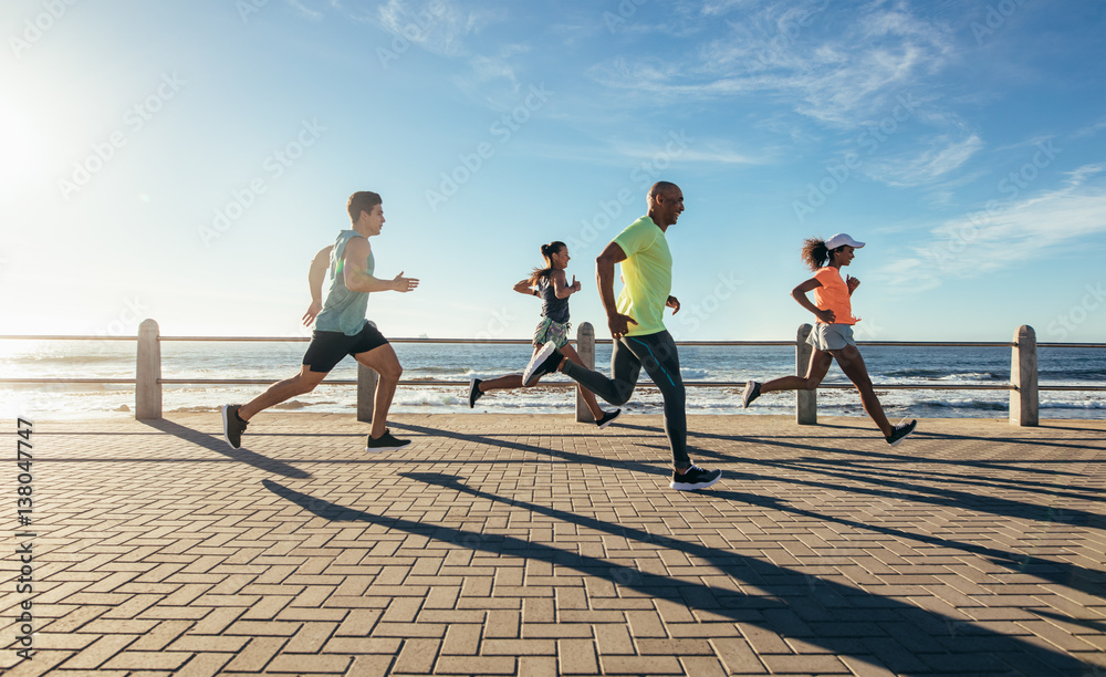 Young people running along seaside