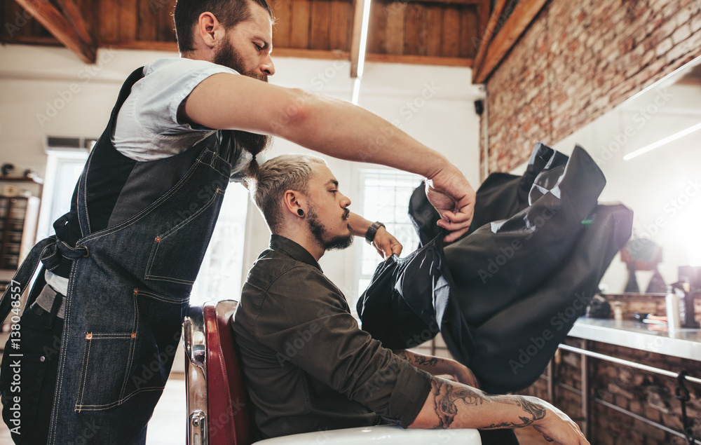 Barber putting salon cape to client