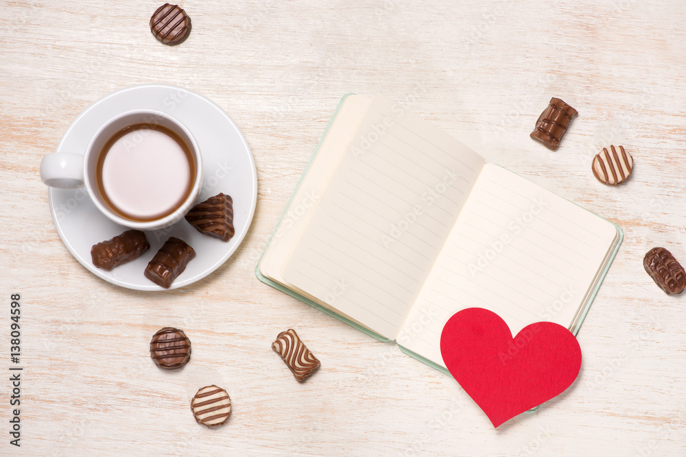 Valentines Day background with chocolate balls, coffee cup, red hearts and notebook