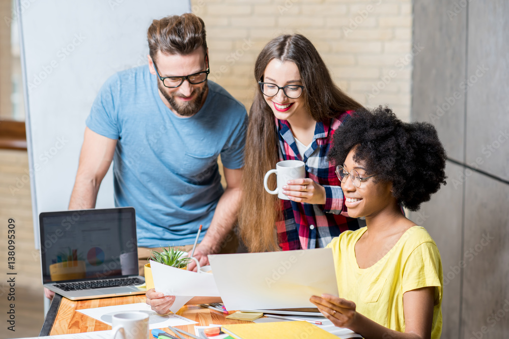 Multi ethnic coworkers dressed casually in colorful clothes working during the meeting at the office