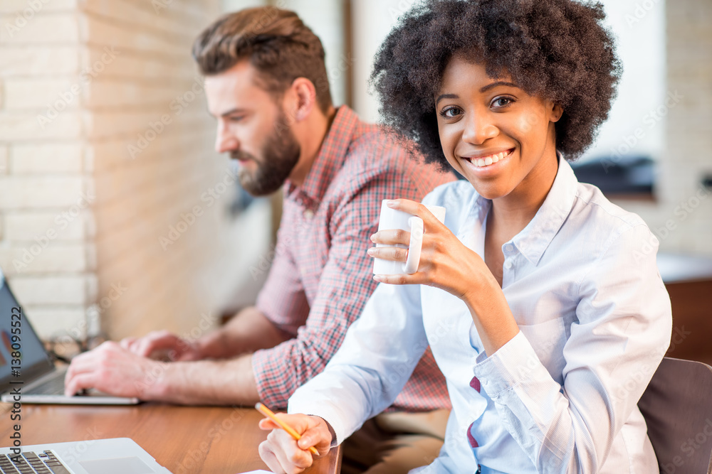 Beautiful african businesswoman and caucasian man working together with laptops and coffee cups near