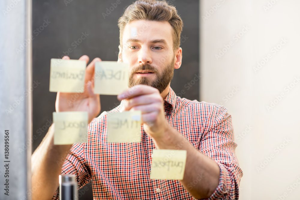 Man working with stickers on the transparent door at the office