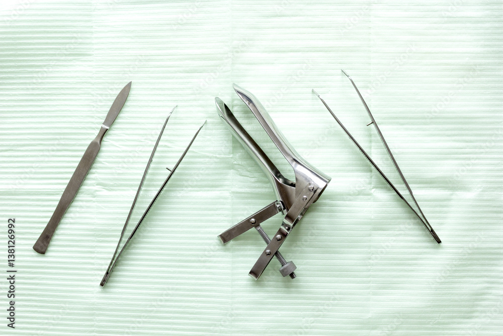 instruments of gynecologist on green background top view