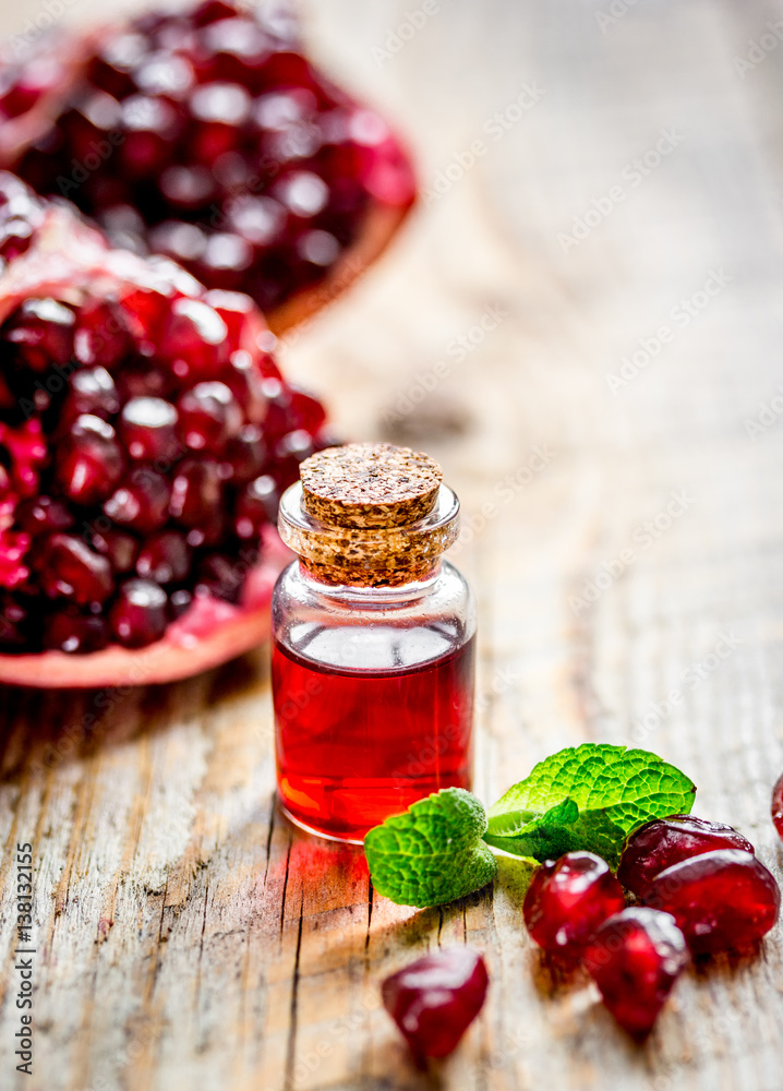 sliced pomegranate and extract in glass on wooden background