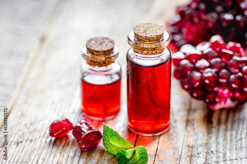 sliced pomegranate and extract in glass on wooden background