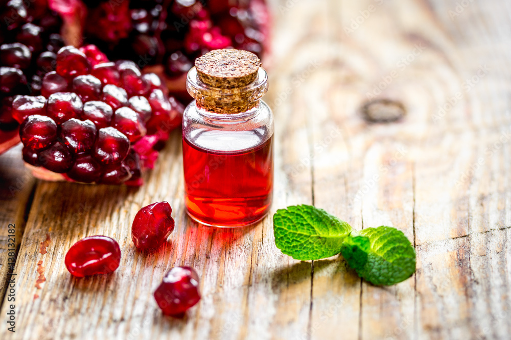 sliced pomegranate and extract in glass on wooden background