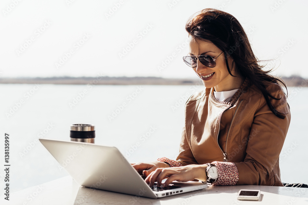 Attractive stylish woman working outside on computer